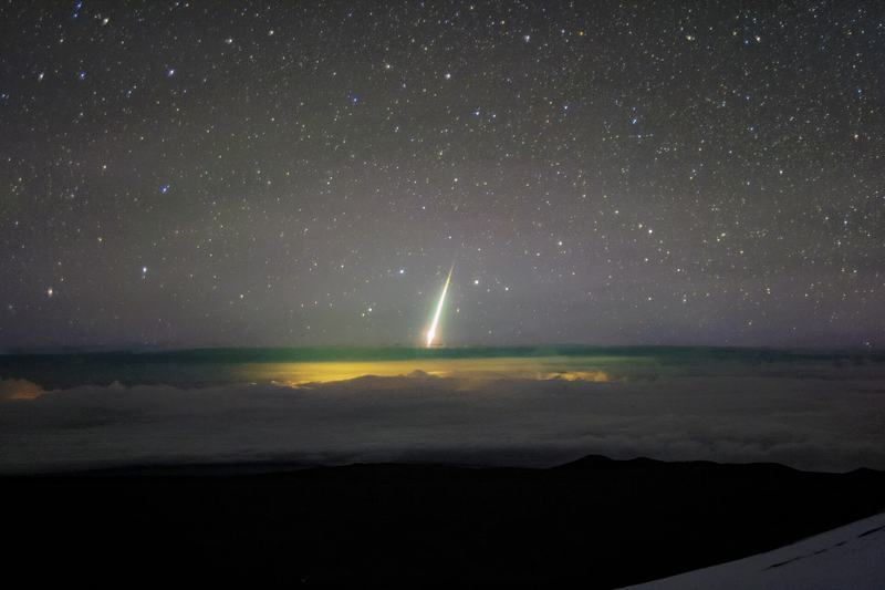Une boule de feu brillante rayer les nuages sous Maunakea, avec les lumières de Hilo, Hawaï, brillant dessous
