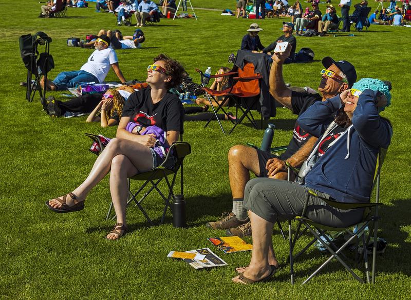 People watching the early phase of the 2017 solar eclipse through eclipse glasses in Rexburg, Idaho