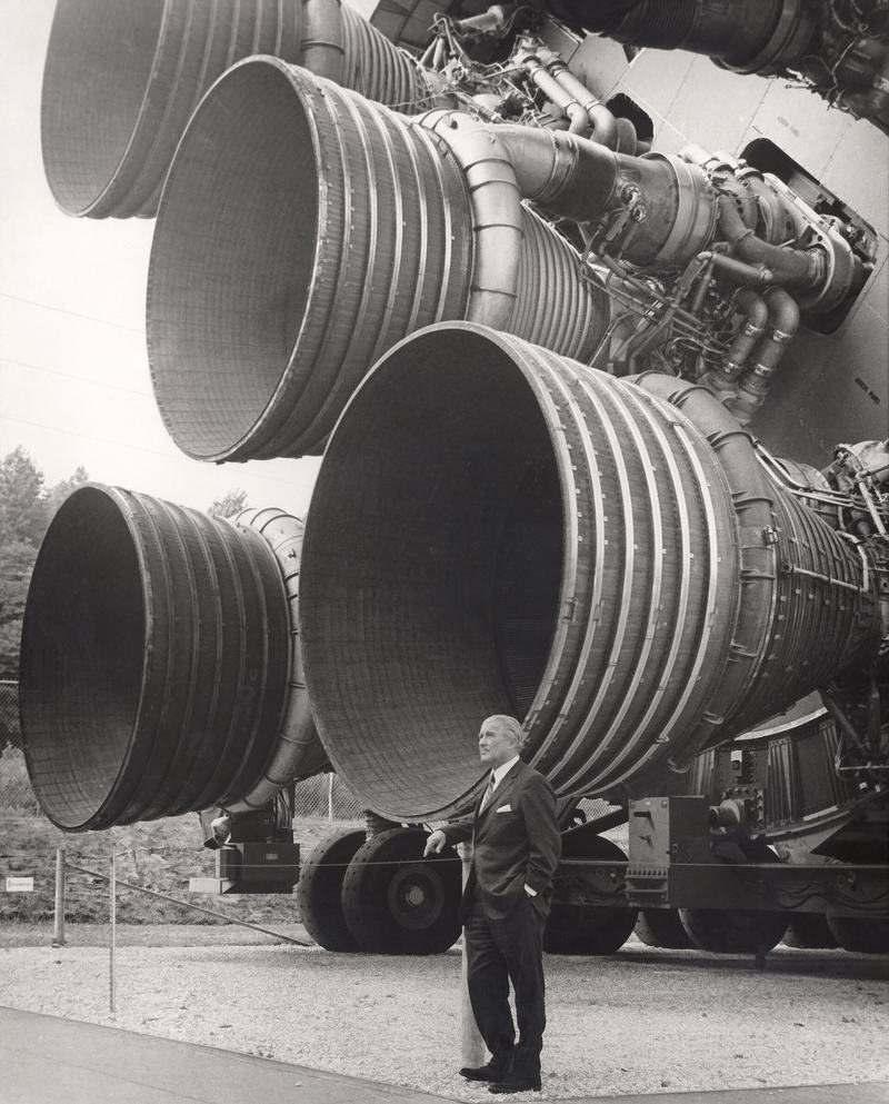 Wernher von Braun standing beside the five F-1 engines of a Saturn V test vehicle