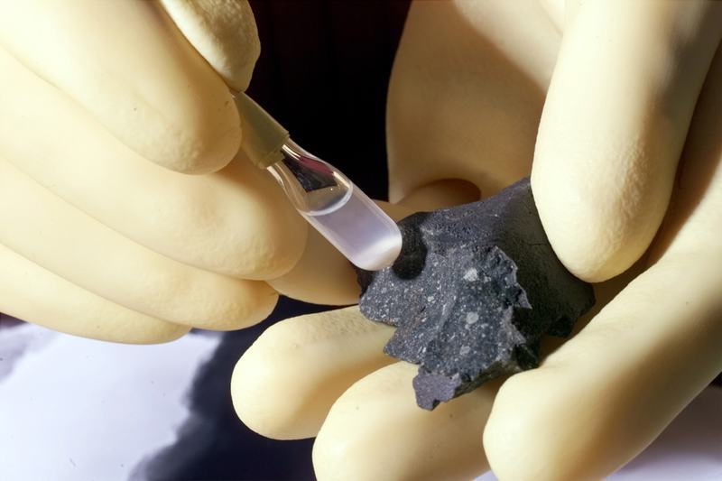 Un fragment sombre de la météorite Murchison à côté d'un tube à essai de particules isolées